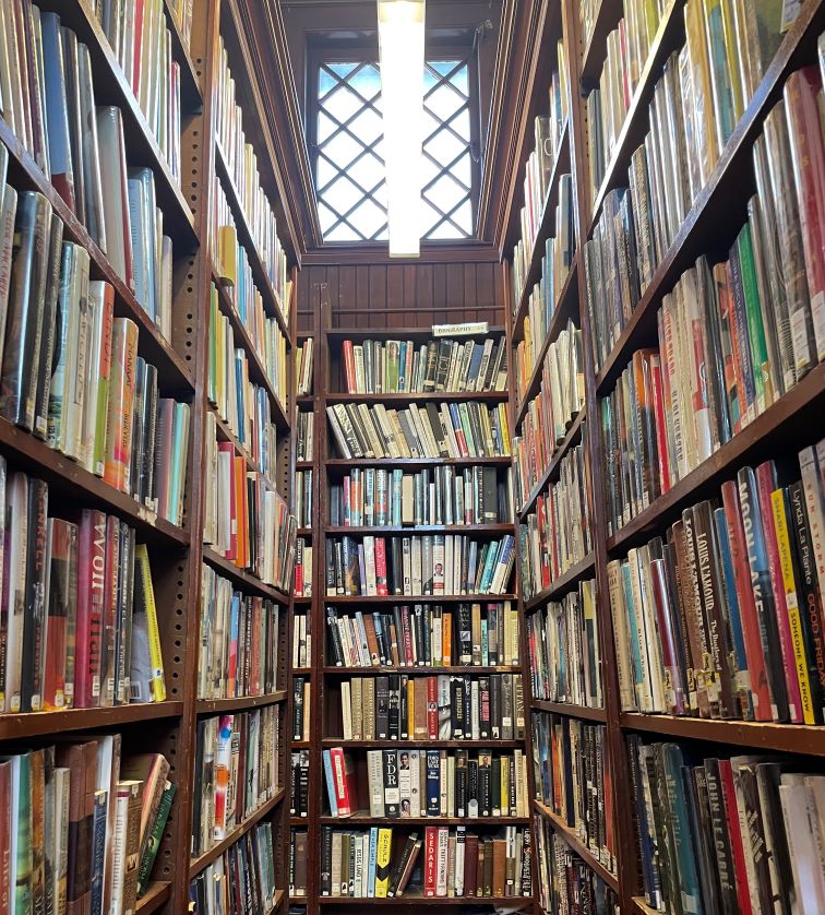 Books line the many shelves in a corner of a library.