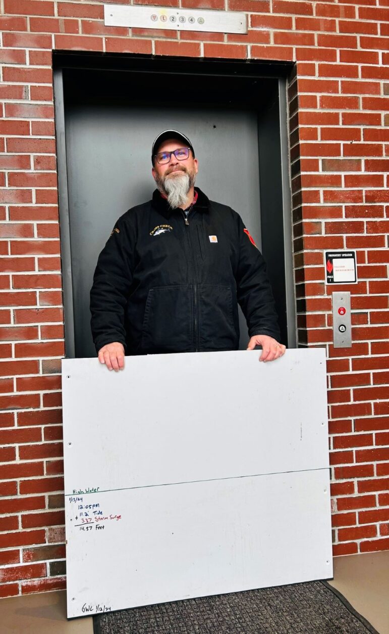 Todd Colpitts stands in front of an elevator while holding a flood gate.