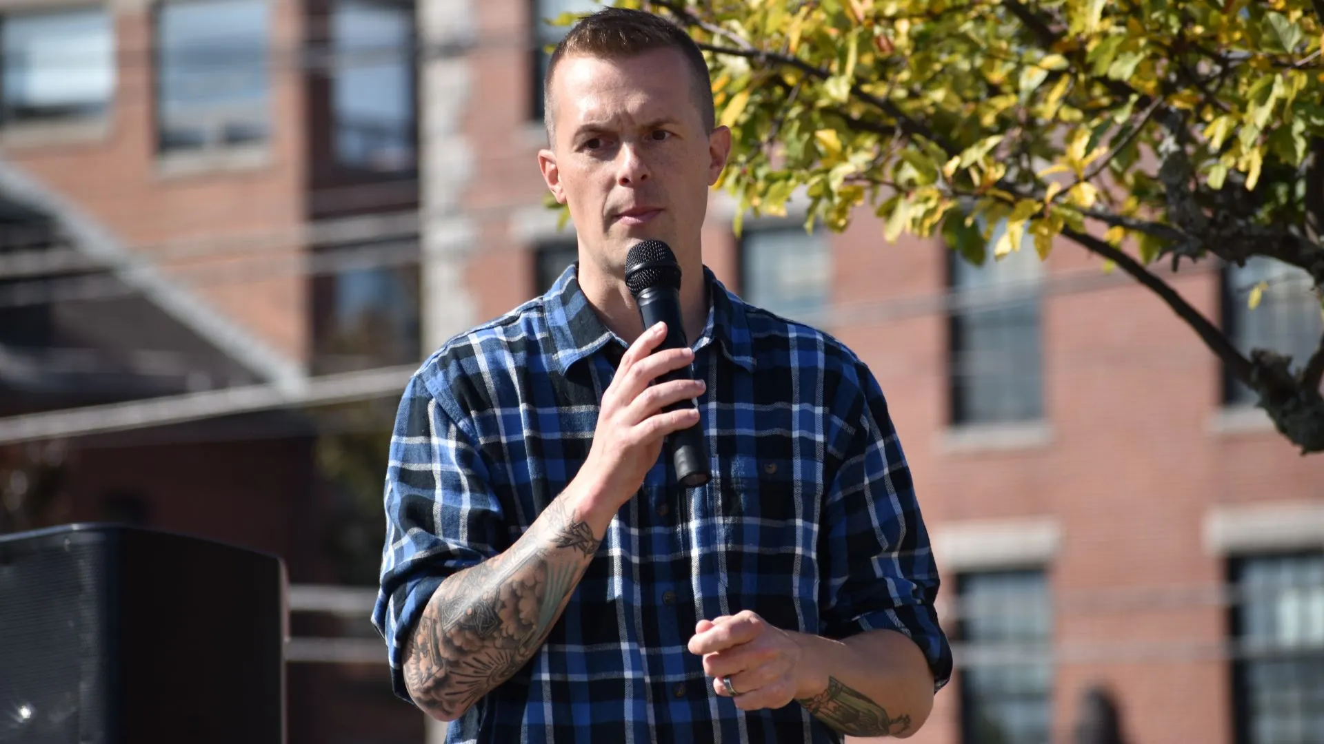 Jared Golden, on stage at a rally, listens to someone in the crowd