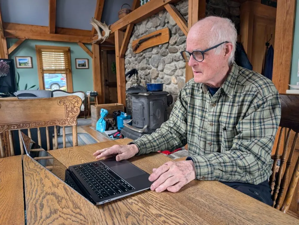Bob O'Brien sits at a table while looking at his laptop.