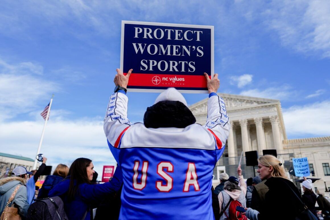 protester holding a sign that reads protect women's sports.