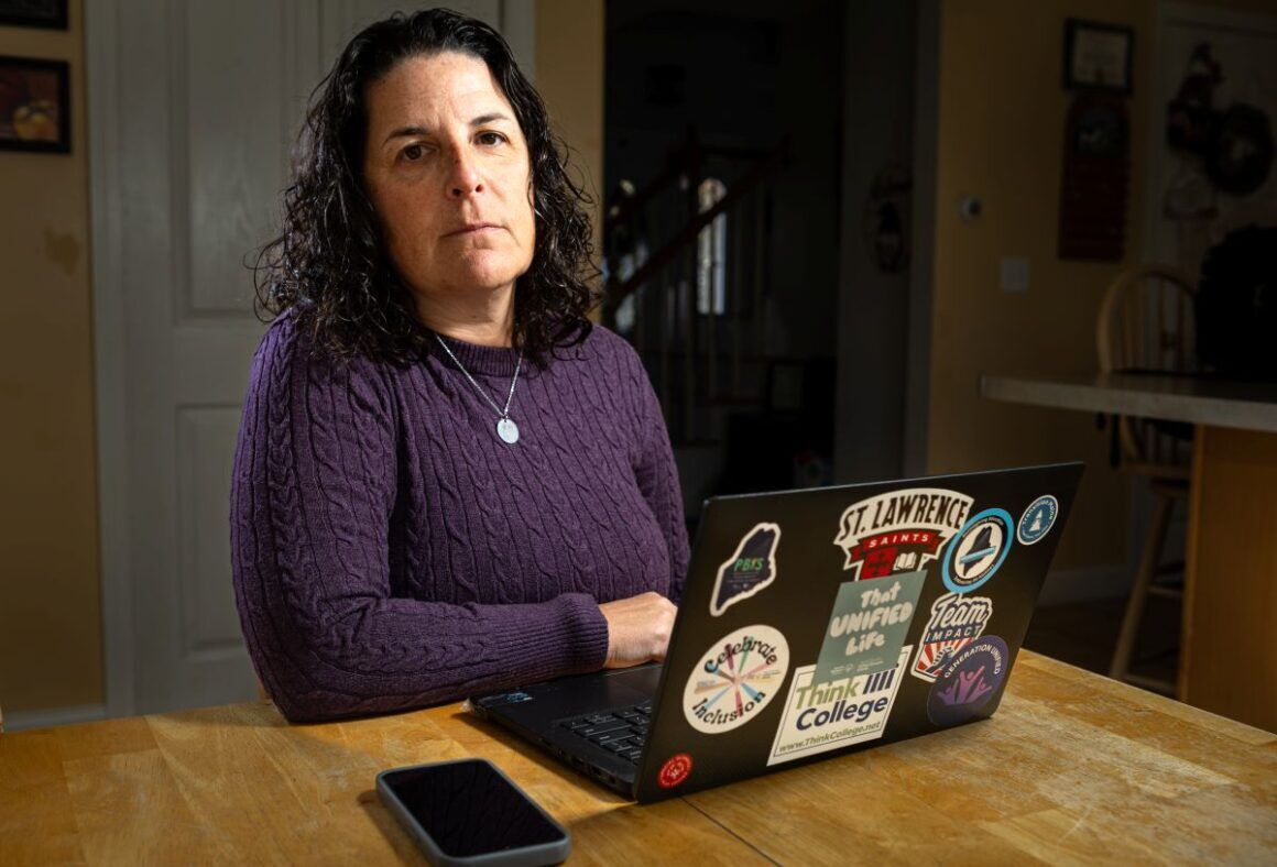 Carrie Woodcock sits in front of her laptop at a table.
