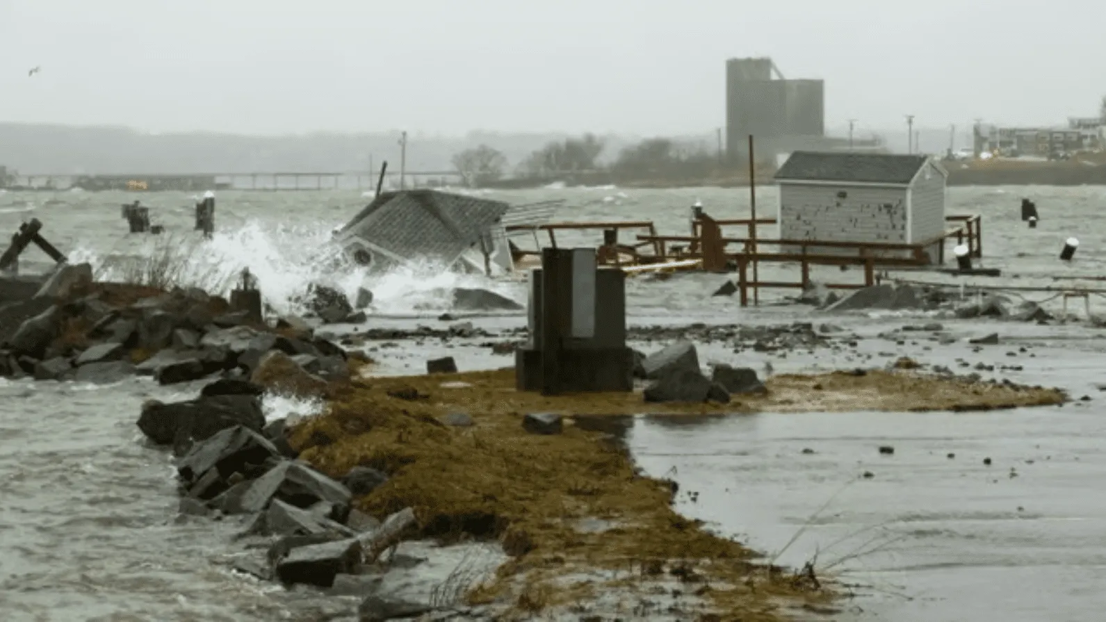 storm surge crashing against, and knocking down, buildings.