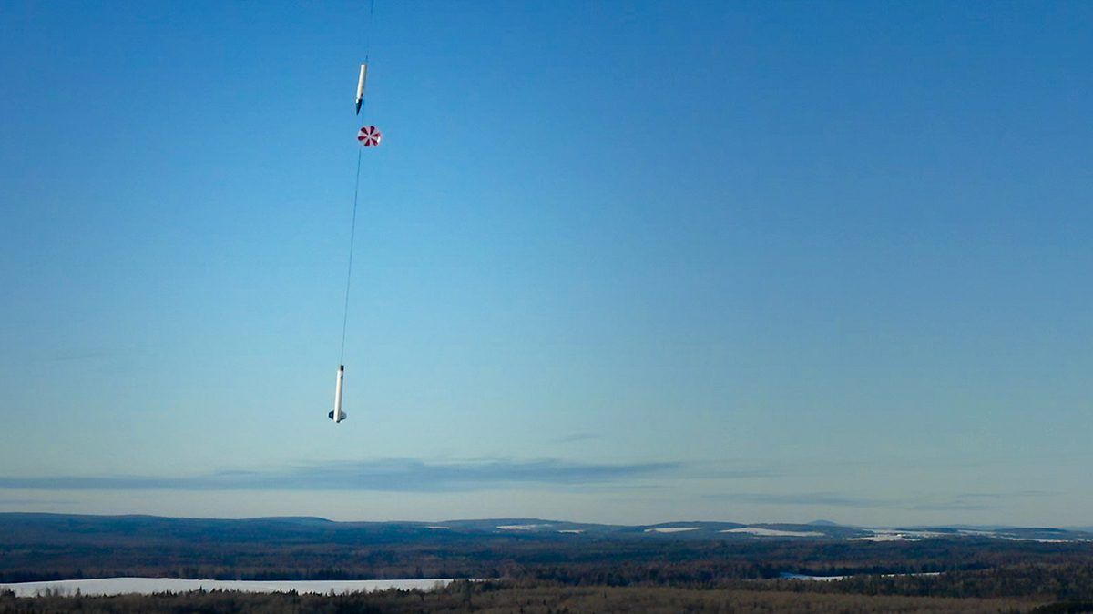 A rocket descends by parachute.