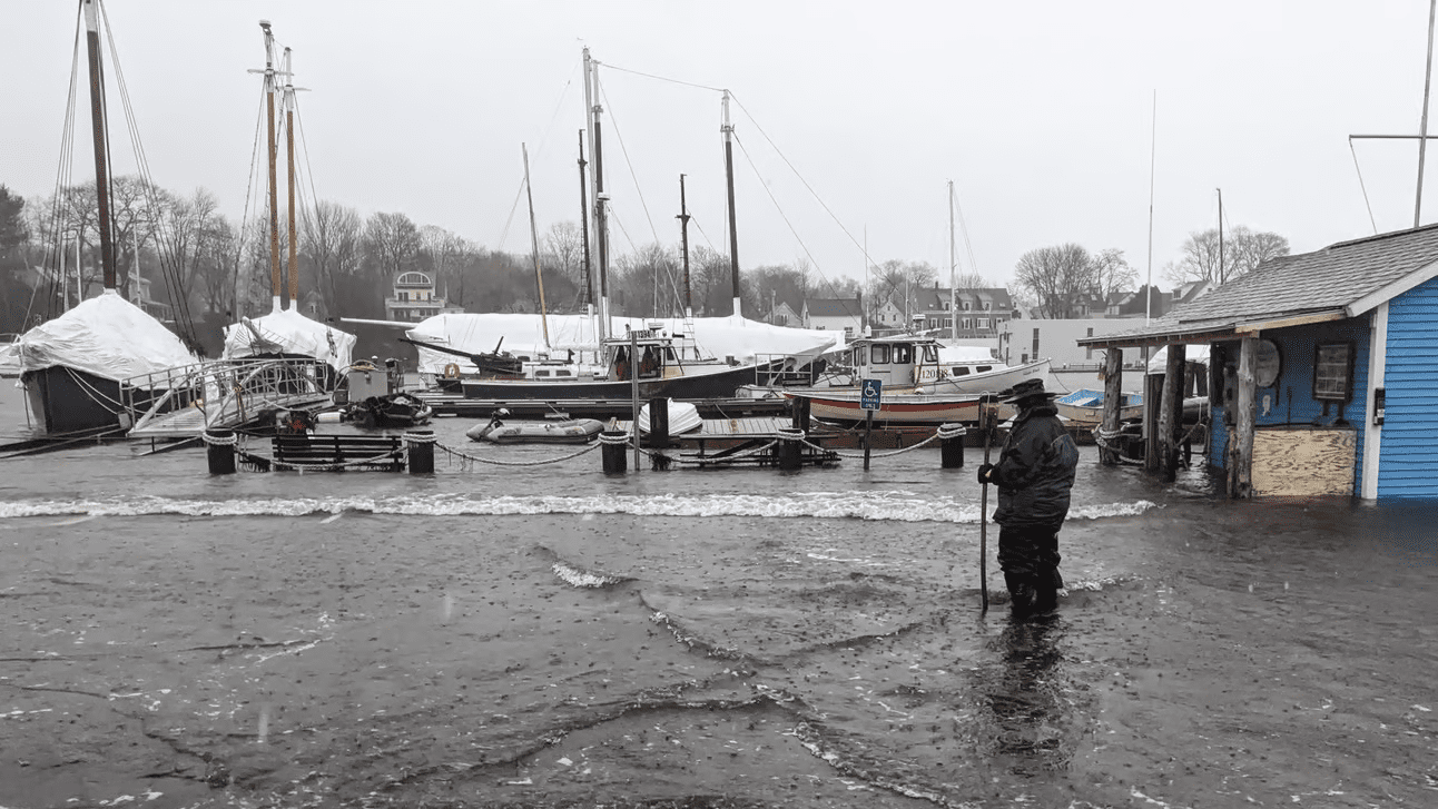 A woman stands in a flooded parking lot.