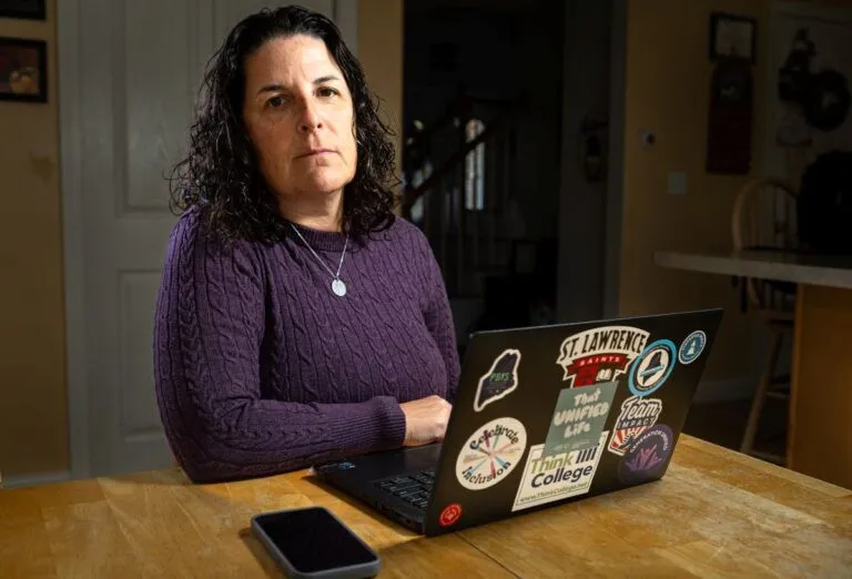 Carrie Woodcock sits in front of her laptop at a table.