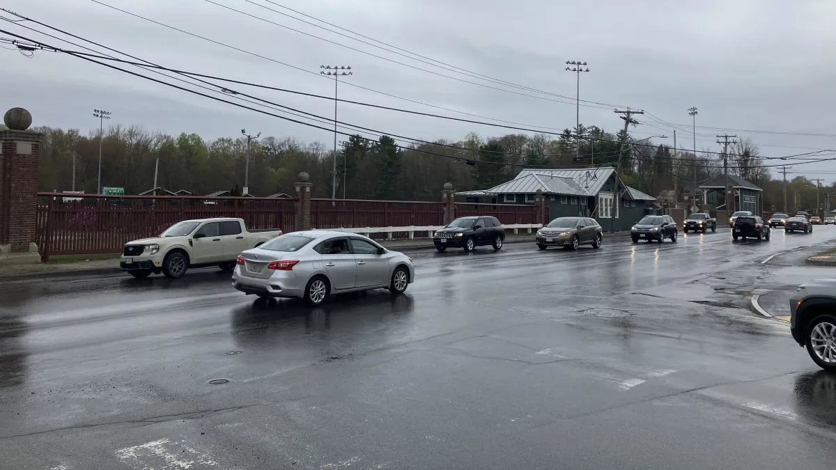 the field's wall seen from across the street as cars pass by.