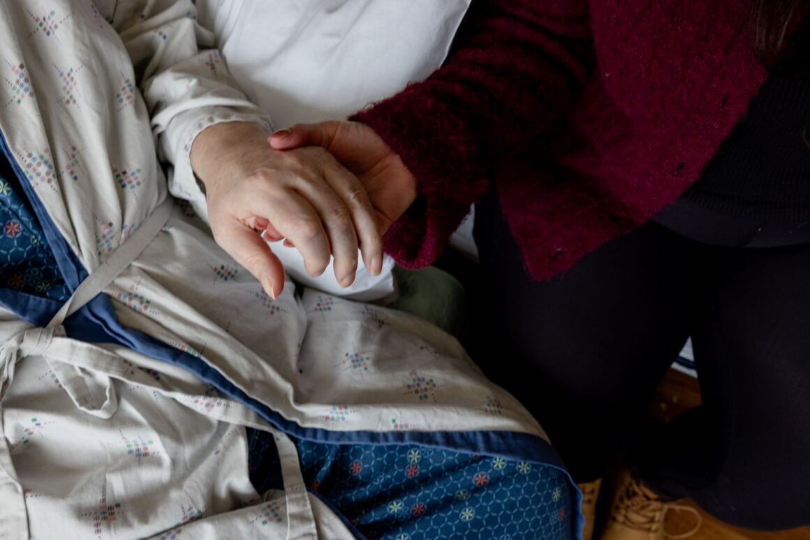a woman holding her father's hand.