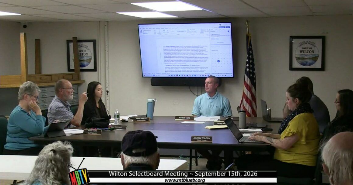 members of the board sit around a table during a meeting.