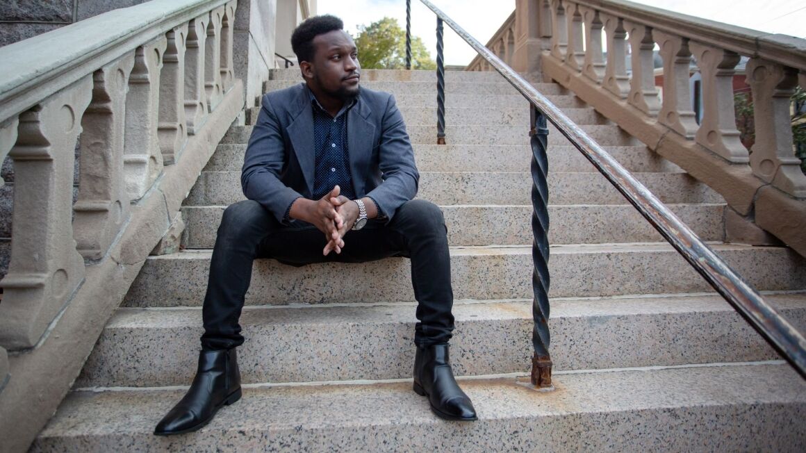 Charles Mugabe sitting on an outdoor staircase, looking to the distance
