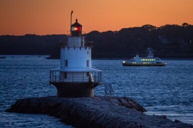 A ferry passes behind a lighthouse.