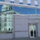 The State House building is reflected through the glass of the Cross office building
