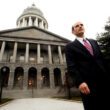 Governor John Baldacci stands in front of the outside of the Maine State House