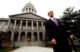Governor John Baldacci stands in front of the outside of the Maine State House
