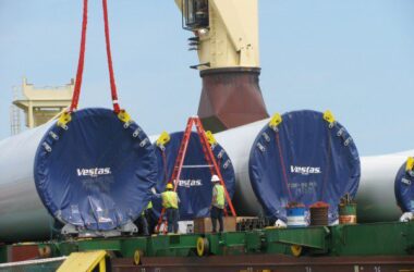 Workers unload tower components for wind turbines