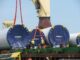 Workers unload tower components for wind turbines