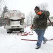 A man walks in the snow while making an oil delivery