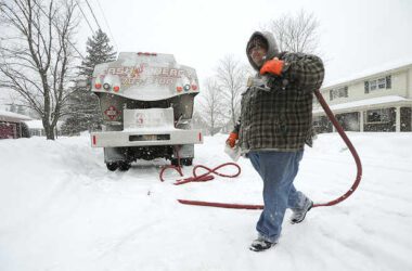 A man walks in the snow while making an oil delivery