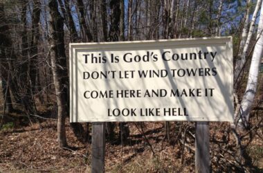 a sign in the woods that reads this is God's country don't let wind towers come here and make it look like hell