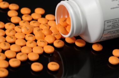 Many orange aspirin pills scattered on a table after being dumped from a bottle.