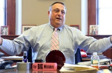 Paul LePage motions with his arms while sitting at his desk