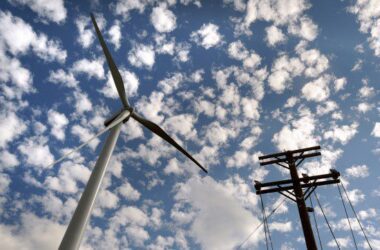 wind turbines and power lines seen looking up from the ground to the sky