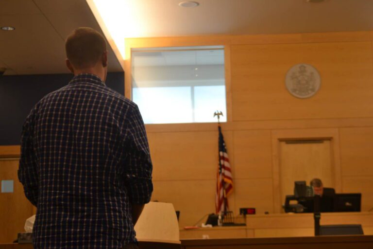 a man stands in appearance before a judge in a court room