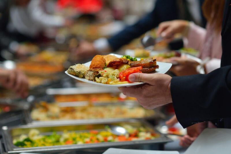 a man holds a plate of buffet food
