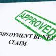 Stock photo of an employment benefits claim form that has been stamped by a green APPROVED ink stamp
