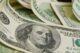 A scattered stack of $100 dollar bills with the image of Benjamin Franklin visible