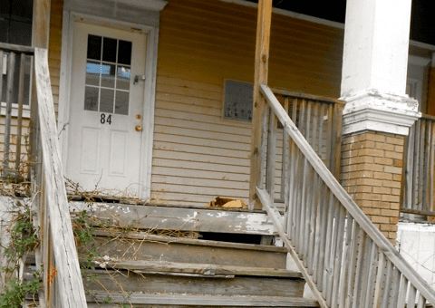 old rundown stairs lead to the entrance of a home