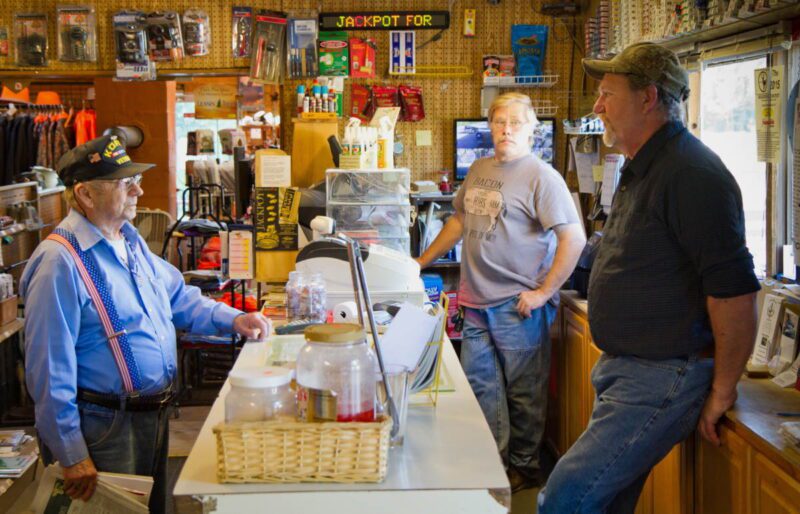three men having a conversation in a general store