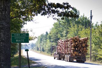 A logging truck crosses the Waite town line. 