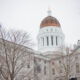 Exterior of the Maine State House during the winter with trees missing all their leaves.