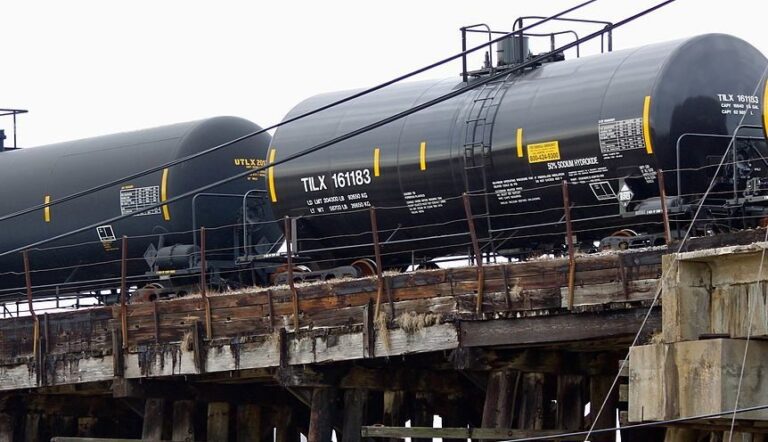 Rail cars carrying oil travel across tracks.