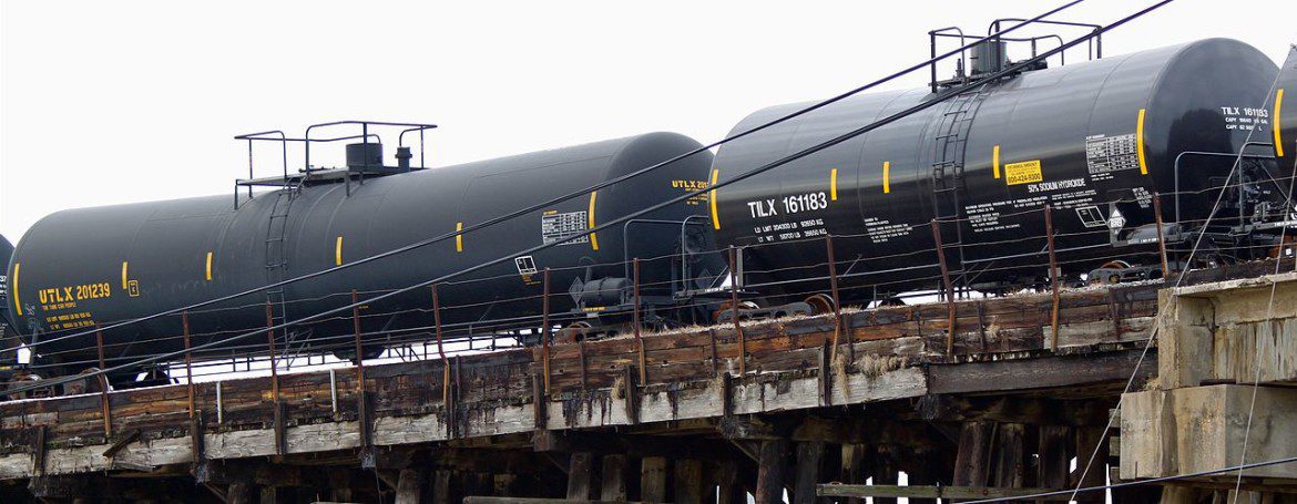 Rail cars carrying oil travel across tracks.
