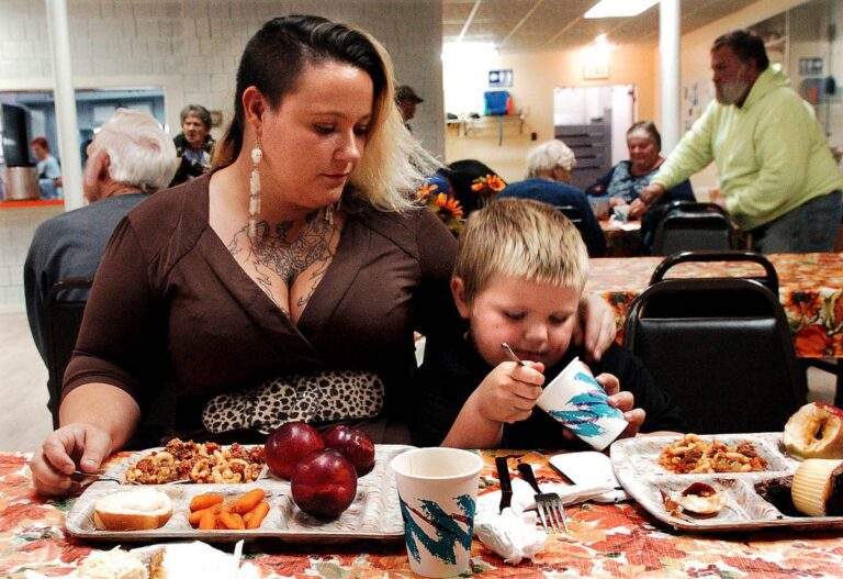 a mother wraps her arm around her son while he eats