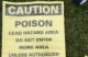 A yellow piece of paper warns individuals of lead poisoning hazards. The sign reads CAUTION POISION LEAD HAZARD AREA DO NOT ENTER WORK AREA UNLESS AUTHORIZED