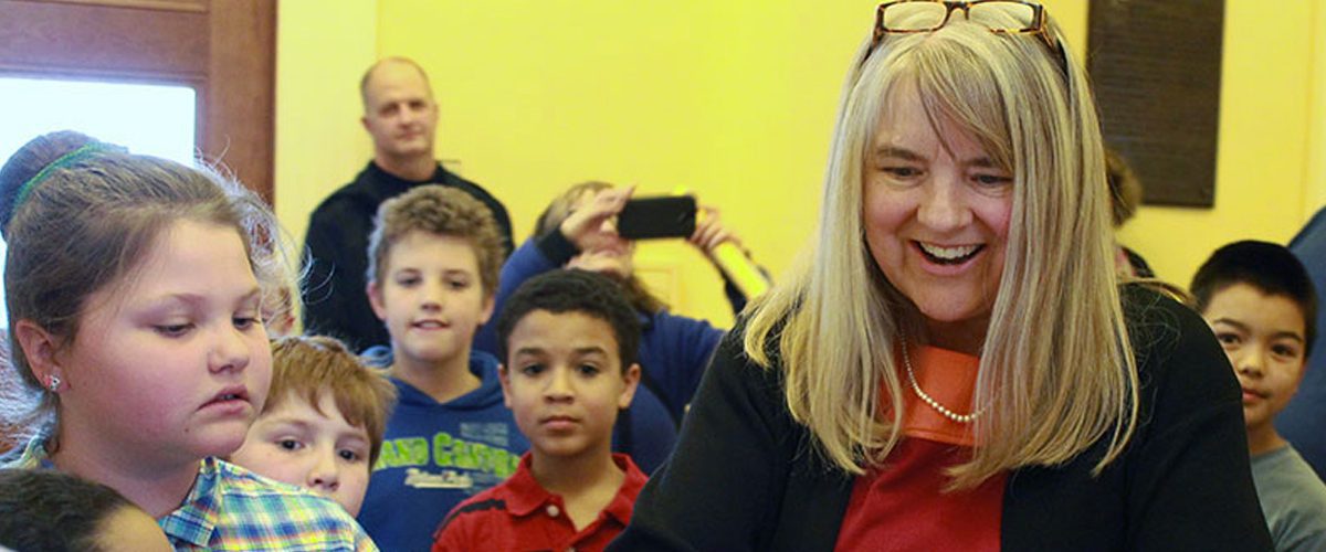 Rebecca Millett greets young students