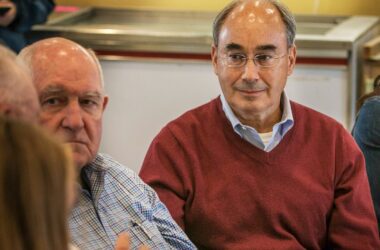Bruce Poliquin, sitting down, listens to a pair of constituents at a campaign event.