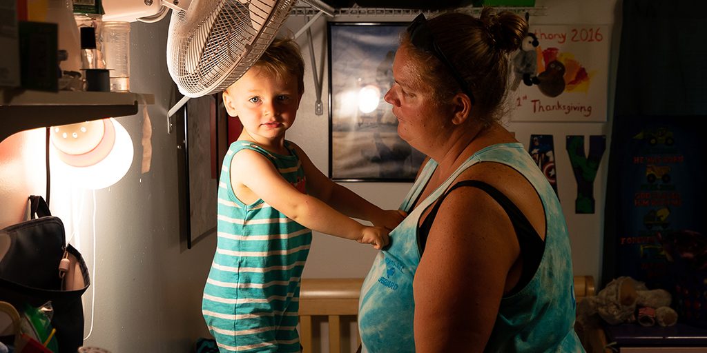Monmouth, ME, United States -- Jay Patrick's "J.P." stands on his changing table with his mother, Lisa Hasch, after he wakes up from his nap in Monmouth, ME on Wednesday, August 8, 2018. Hasch adopted J.P. and his older brother Devon, and J.P. was an NAS baby who arrived at 4 weeks with withdrawal symptoms that included tremors, rashes, vomiting and constant screaming. J.P. got a feeding tub in July 2017 which improved his quality of life. (Photo by Yoon S. Byun)