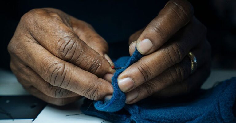 a pair of hands sewing an item of clothing by hand