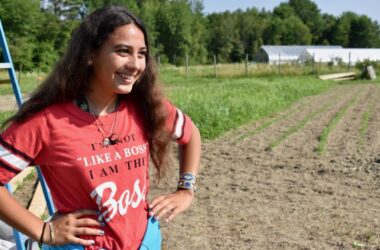 Patience Goulette poses for a photo while standing amid a field of crops.