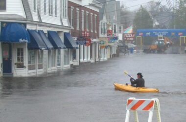 a man in a kayak paddles across a flooded street