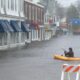a man in a kayak paddles across a flooded street