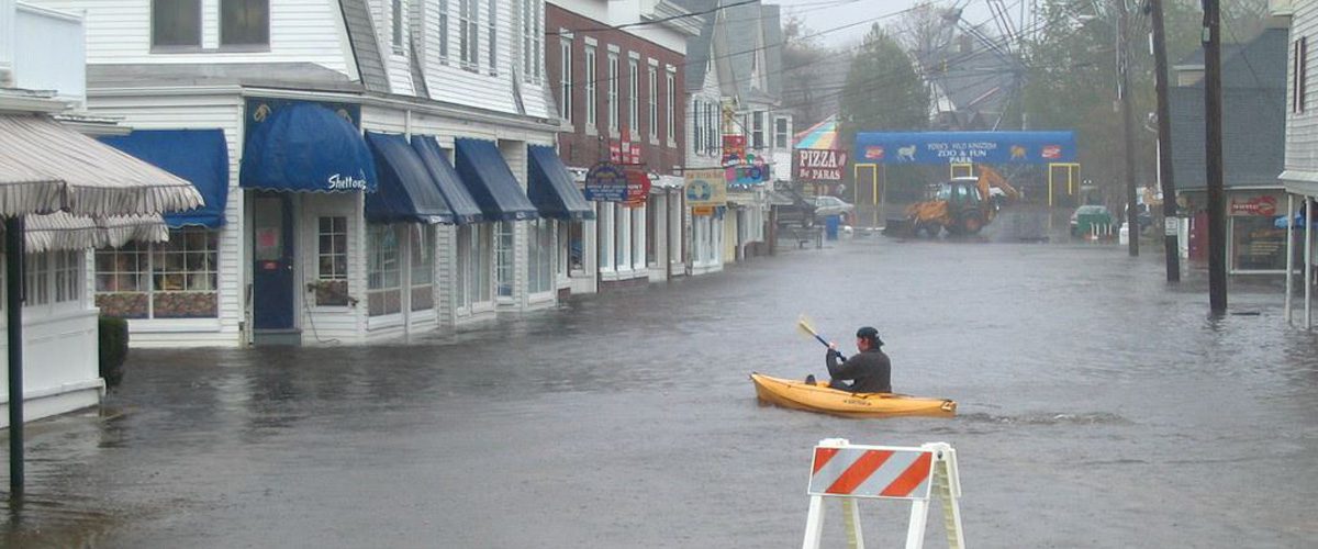 a man in a kayak paddles across a flooded street