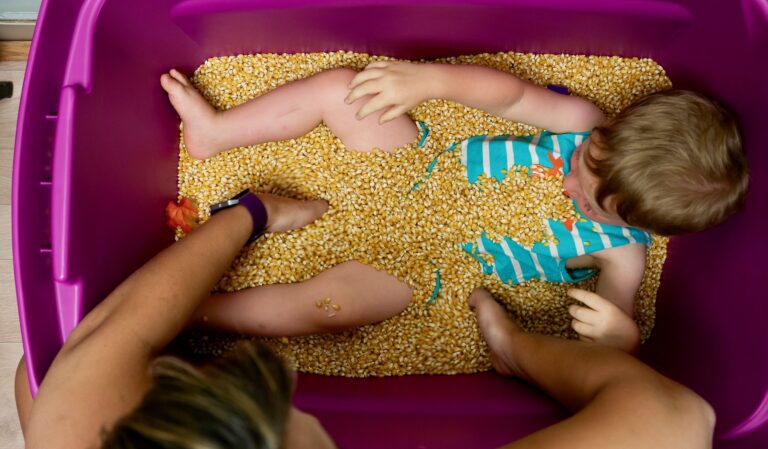 young boy sits in a tub of corn