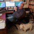 Russ Murley looks at his dog while he sits in his home office