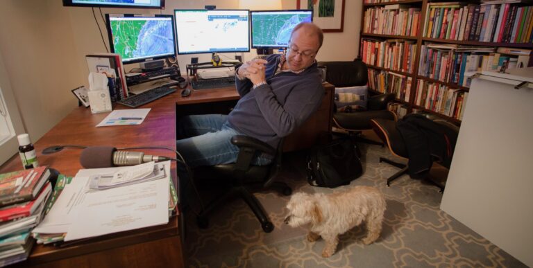 Russ Murley looks at his dog while he sits in his home office