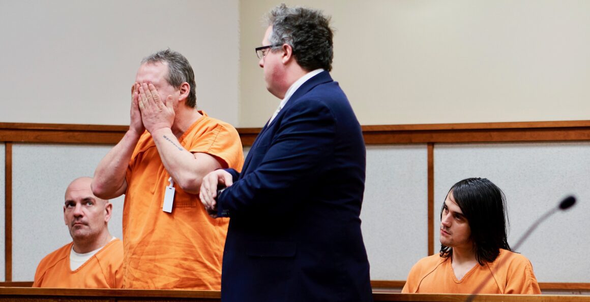 A defendant holds his face in his hands
